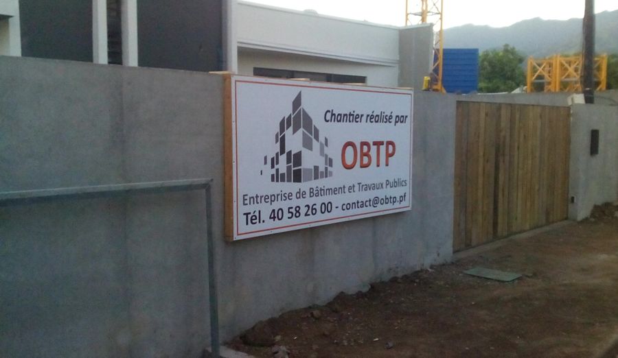 Le panneau de chantier OBTP sur le mur de clôture